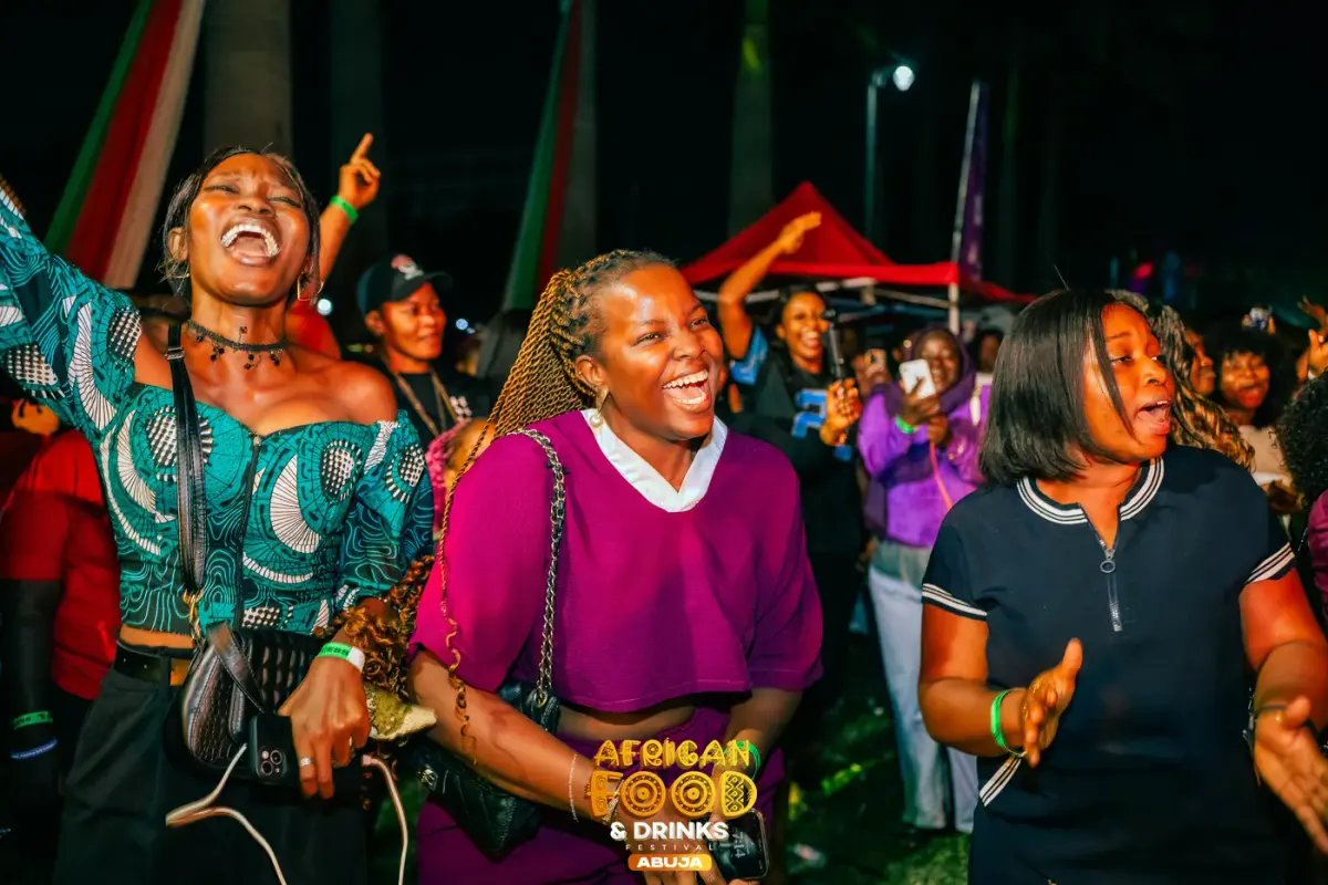 Three guests dancing and singing together at night, the stage lights behind them