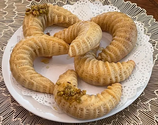 Algerian Tcharek M'saker crescent almond cookies dusted with icing sugar, traditional North African celebration biscuits