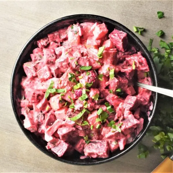 South African Creamy Beet and Potato Salad in a bowl, vibrant pink from roasted beetroot with a creamy dressing