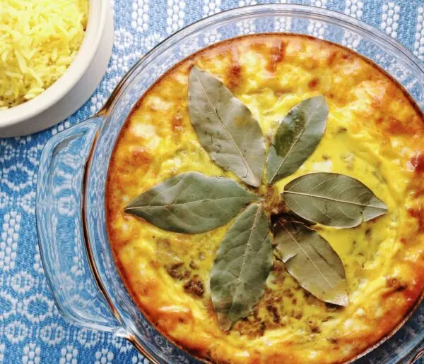 Bobotie South African spiced minced meat bake with egg custard topping served with yellow rice and chutney, South Africa's national dish