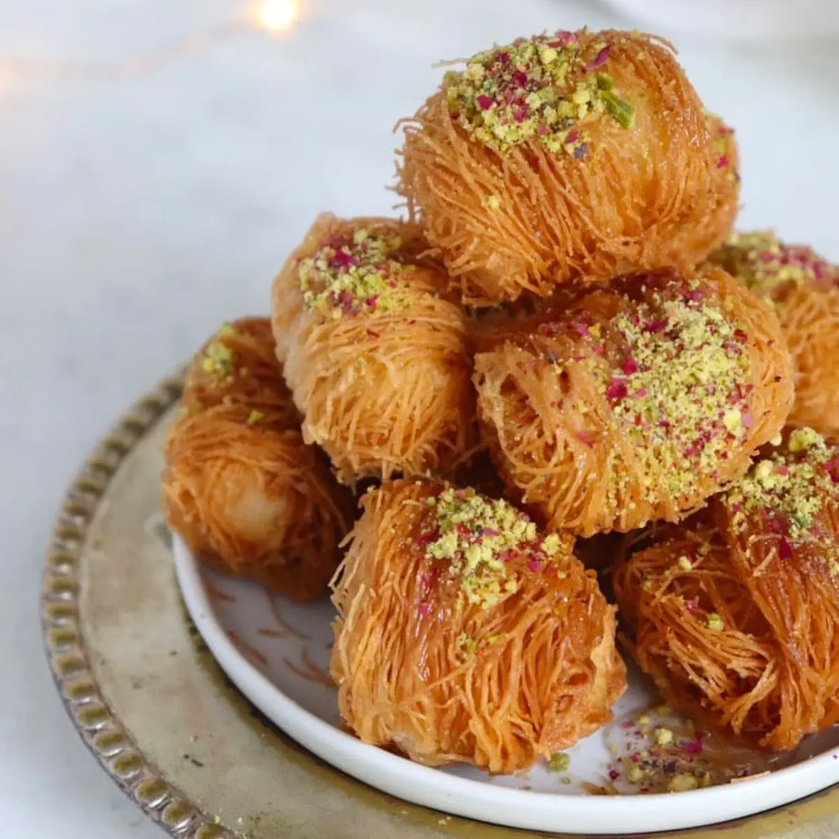 Egyptian Kanafeh golden shredded pastry with cheese filling soaked in syrup in a round baking dish, a beloved North African dessert