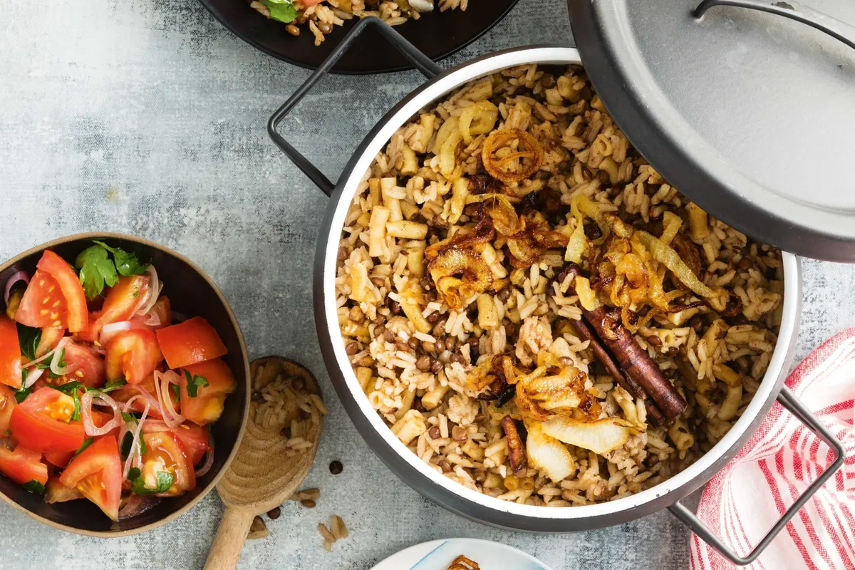 Egyptian Koshari in a bowl with rice, lentils, pasta, and spiced tomato sauce topped with crispy fried onions