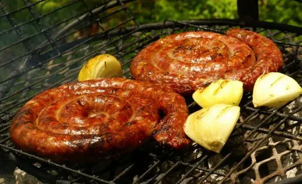 Boerewors, a coiled South African beef sausage seasoned with coriander, grilling over coals