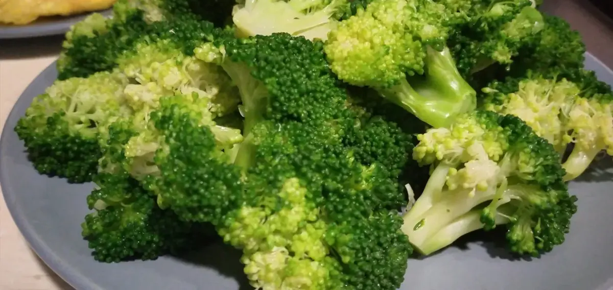 Bright green boiled broccoli florets in a colander