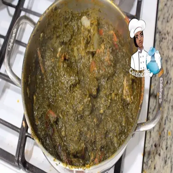 Cassava leaf soup, a thick West African stew of pounded cassava leaves with palm oil and smoked fish, served over rice