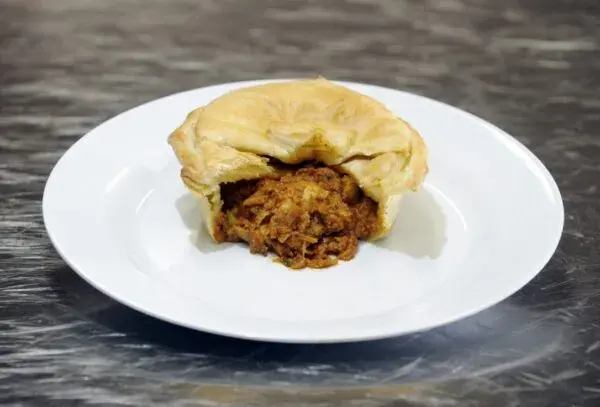 South African chicken pie with a golden puff pastry lid, filled with chicken, ham and egg in a sago thickened sauce