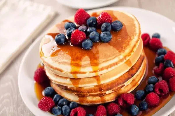 A stack of fluffy pancakes cooked in butter and served warm