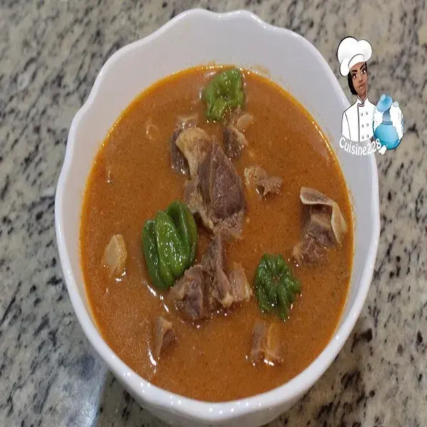 Ivorian pepper soup, a thick spiced goat meat broth with crushed aubergine, tomato and onion