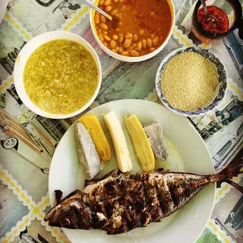 Mufete, an Angolan dish of grilled fish with onion salsa, beans, plantain and cassava on a sharing platter