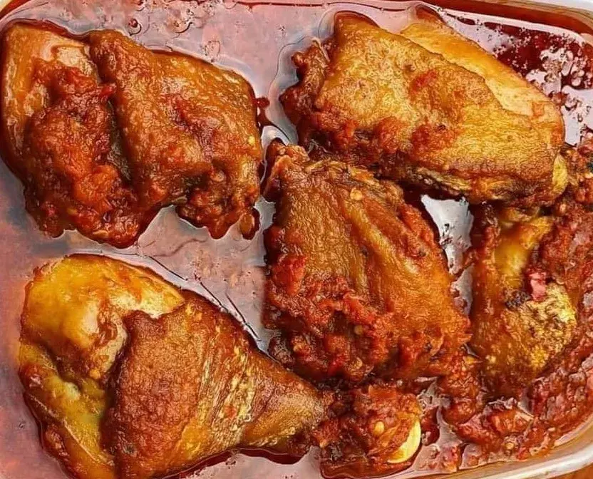 Nigerian chicken stew, a deep red tomato and pepper stew with fried chicken, served with rice
