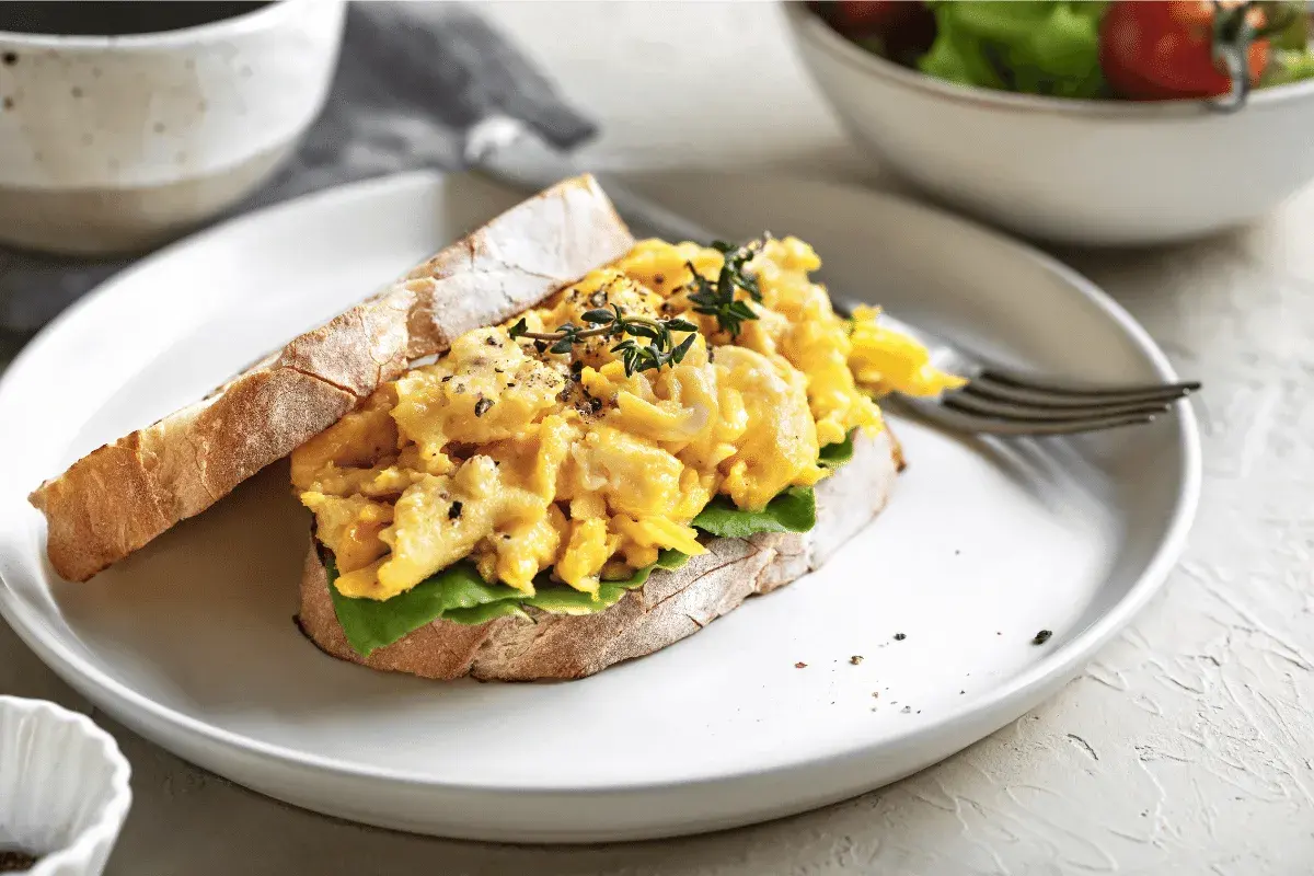 Scrambled egg sandwich with cheddar and pesto on toasted bread