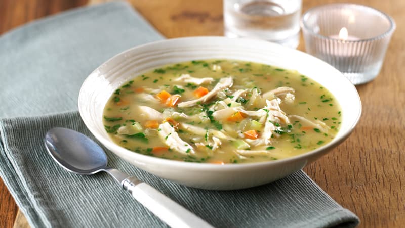 South African Chicken Soup with noodles, vegetables, and golden broth in a bowl, a hearty homemade winter comfort