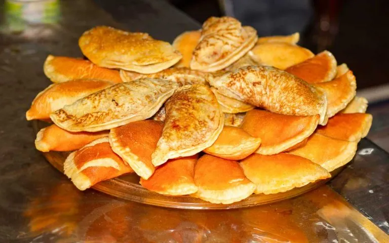 Egyptian Katayef stuffed mini pancakes filled with cheese and drizzled with syrup on a plate, a beloved Ramadan dessert