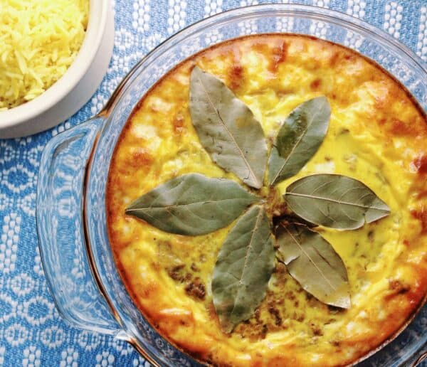 Bobotie South African spiced minced meat bake with egg custard topping served with yellow rice and chutney, South Africa's national dish