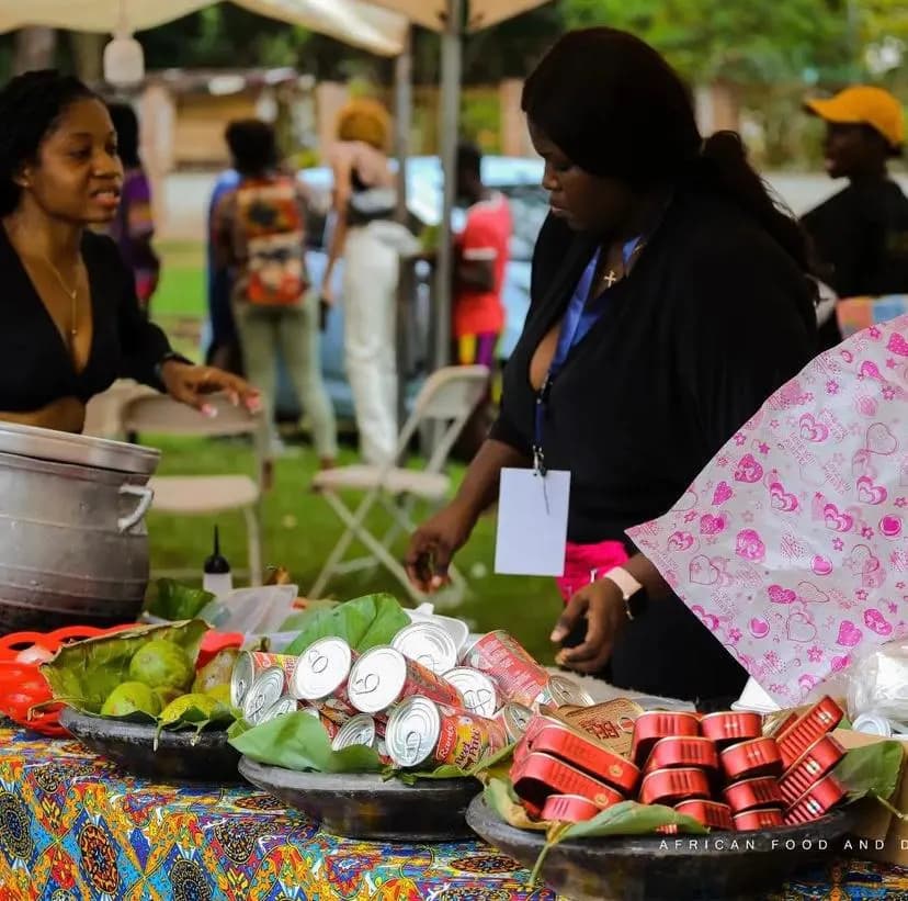 La table d'un stand chargée de citrons verts et de boissons en canette, les marmites derrière et une serveuse au comptoir