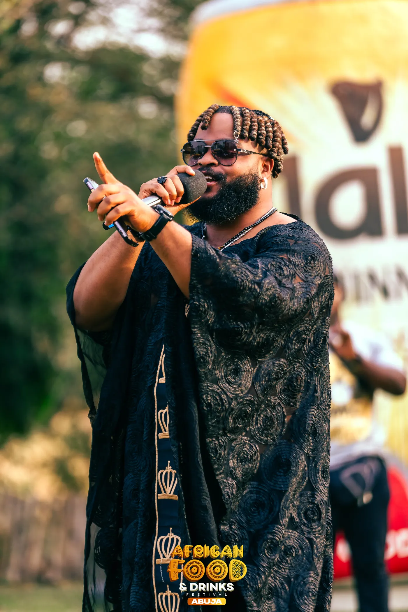 Un chanteur en boubou à motifs tient un micro devant le fond African Food Network