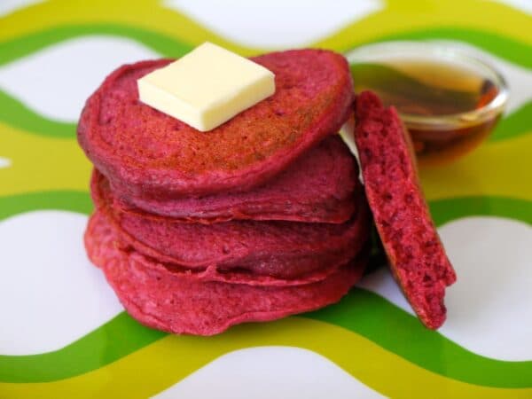 South African Beetroot Pancakes stacked on a plate, naturally coloured pink from roasted beetroot with maple syrup