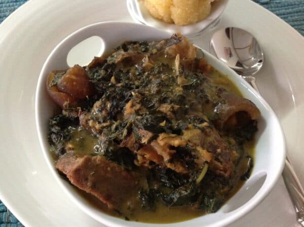 Nigerian Bitter Leaf Soup (Ofe Onugbu) in a pot with assorted meat, cocoyam thickener, and washed bitter leaves from southeastern Nigeria