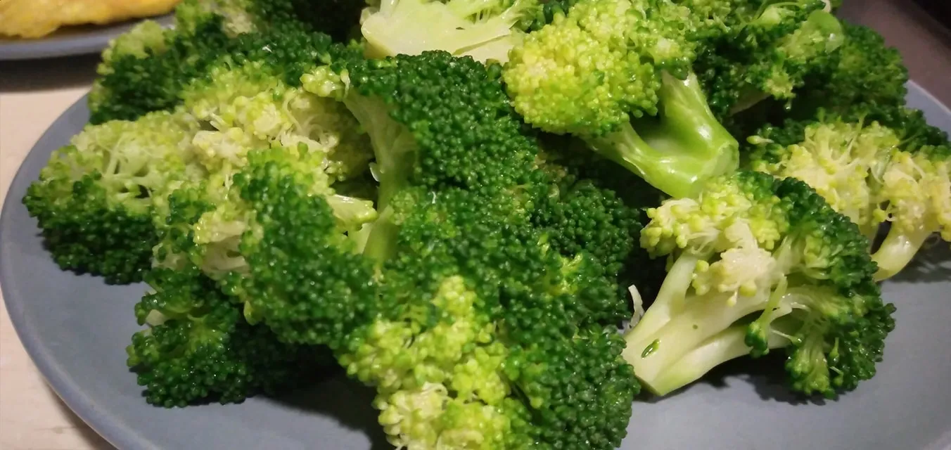 Bright green boiled broccoli florets in a colander