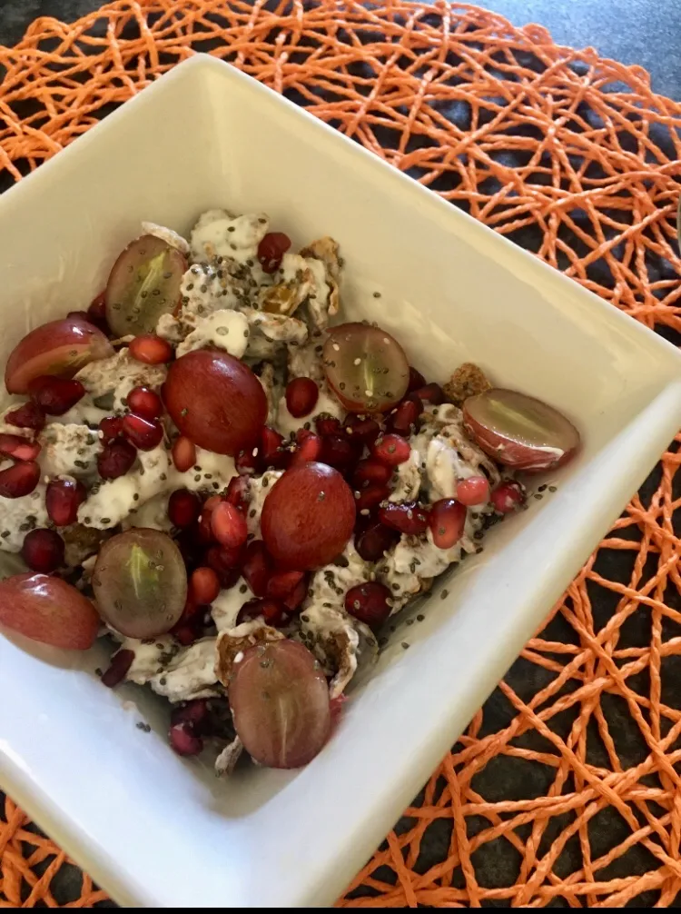 Bran flakes with plain yoghurt, halved grapes, pomegranate seeds and chia