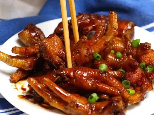 Braised chicken feet in a dark soy and star anise sauce, garnished with scallions and sesame seeds
