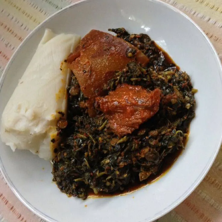 Eko or agidi, sliced Nigerian fermented corn pudding, served with efo riro vegetable stew