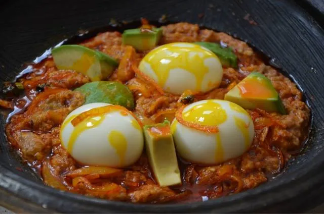 Ghana abom, ground cocoyam leaves with palm oil, served with boiled plantain, egg, fish and avocado