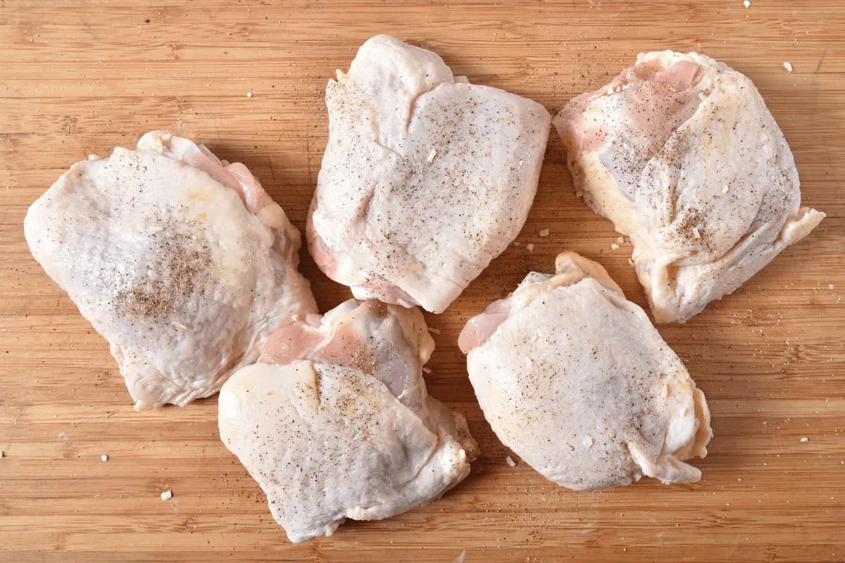 Boiled chicken thighs served with lemon wedges and parsley