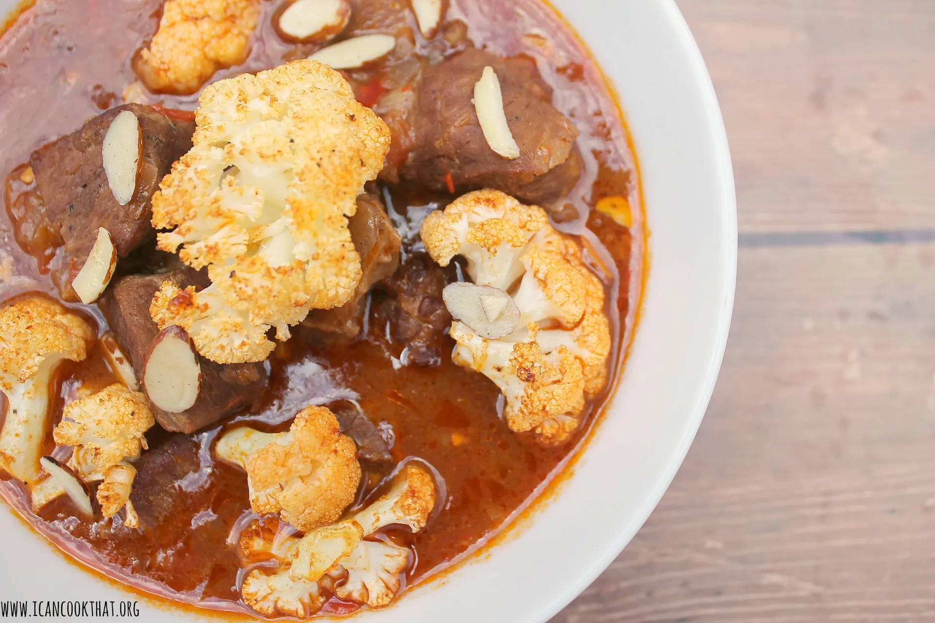 Lamb stew with harissa, topped with charred cauliflower and toasted almonds