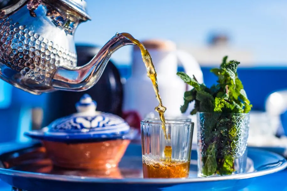 Moroccan mint tea poured into a glass with fresh spearmint