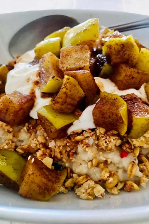 Oatmeal made with water, topped with cinnamon apples, yoghurt and muesli