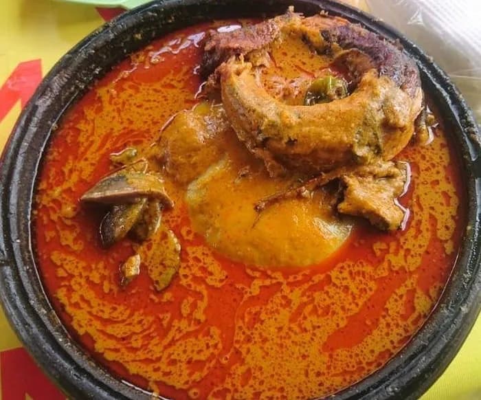 Palmnut soup, known in Ghana as abenkwan, a rich orange soup of palm fruit pulp with fish and meat, served with fufu