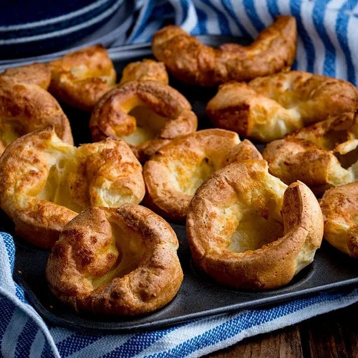 Yorkshire puddings risen tall and golden in a muffin tin